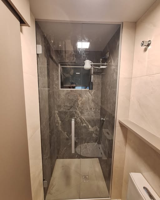 Box de banheiro frameless sobre porcelanato marmorizado escuro