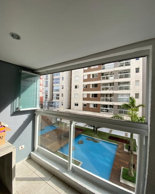 Sacada envidraçada com esquadria branca e vista para piscina de condomínio